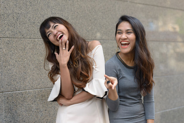 有趣两位年轻的亚洲女商人在城市户外的合影朋友泰国在一起