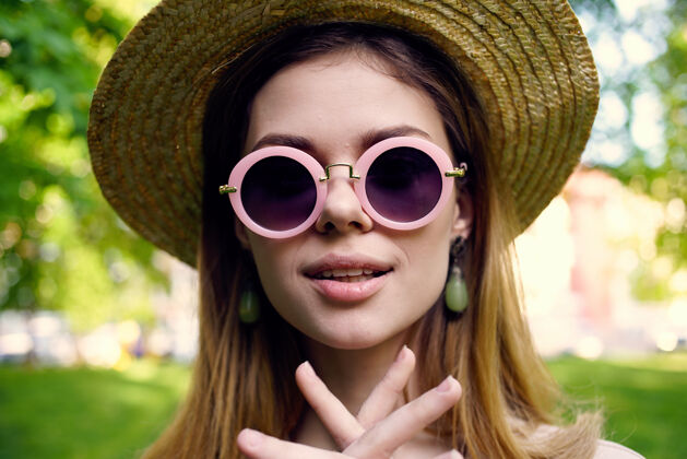 可爱快乐的女人戴着太阳镜在公园草地上散步女人公园肖像