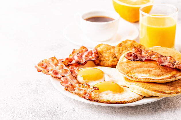 盘子健康丰盛的美式早餐 有鸡蛋 培根 煎饼和拿铁 有选择的重点薯条棕色培根
