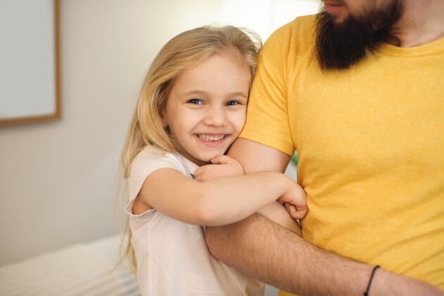 玩耍早上在家里 可爱的金发小女孩微笑着拥抱着父亲的手爸爸父母胡须