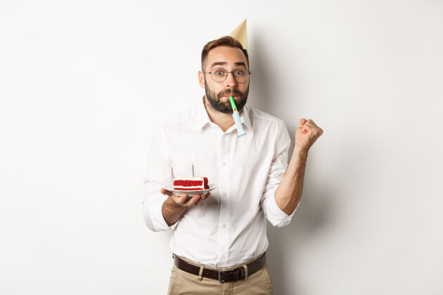 帽子节假日庆祝开朗男人享受生日 吹派对哨子 拿着生日蛋糕 白色背景活动欢呼蛋糕