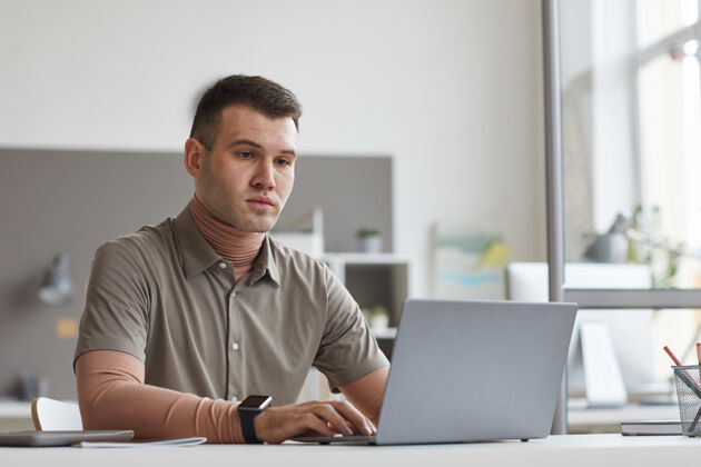 使用笔记本电脑年轻人坐在办公室里用笔记本电脑打字 他在办公室上网商务人士办公桌技术