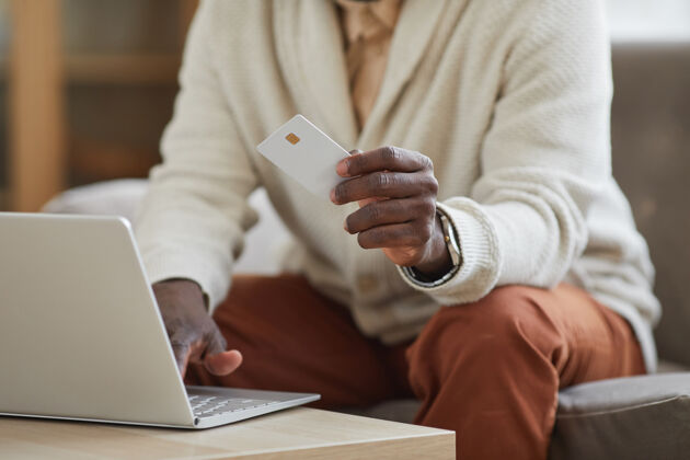 技术商人坐在笔记本电脑前用信用卡在线支付的特写镜头购买人手互联网