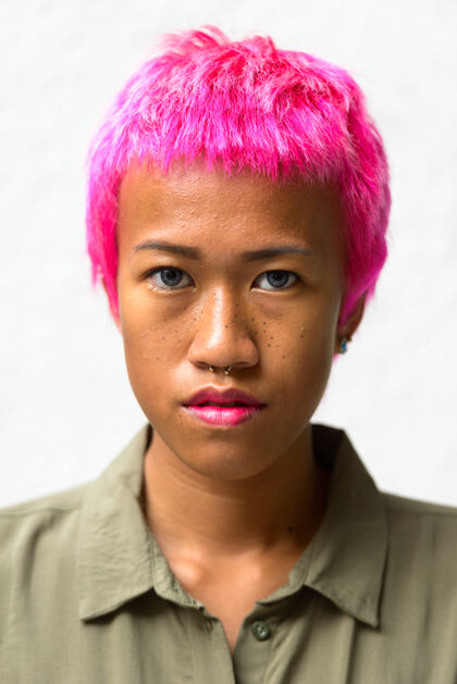 时髦年轻叛逆的亚洲女人的肖像 粉色的头发映衬着白色的空间墙发型古怪