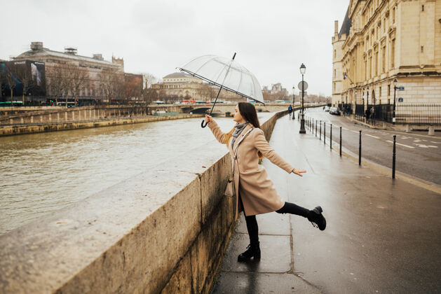 地标快乐漂亮的女孩拿着透明的雨伞在外面散步桥梁城市景观天空