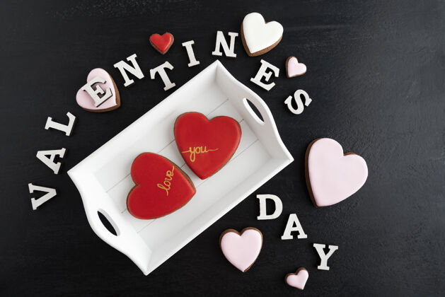 庆祝情人节的题词来自字母和姜红色心形饼干的黑色背景霜姜心形