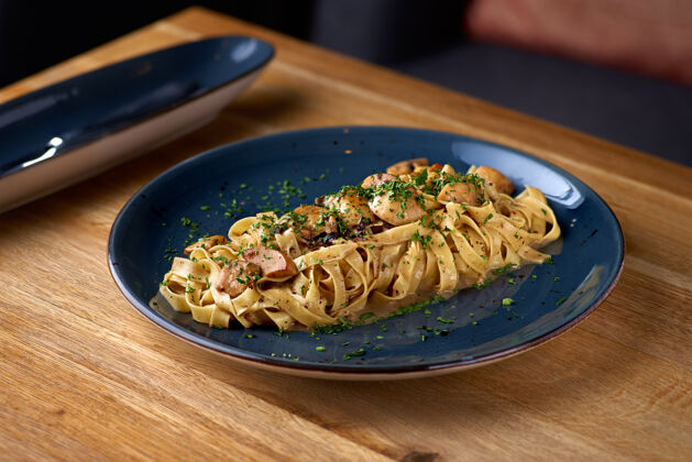 烹饪桌上放着蘑菇和帕尔玛干酪的意大利面 在餐馆里供应真菌水平森林