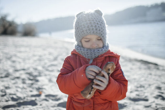 快乐冬天 孩子在沙滩上散步 寒冷的温度和阳光明媚的日子编织帽子寒冷孩子们