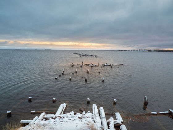 地平线冬季简约的夜晚景观 在白海中有一个破旧的码头破坏单色防御