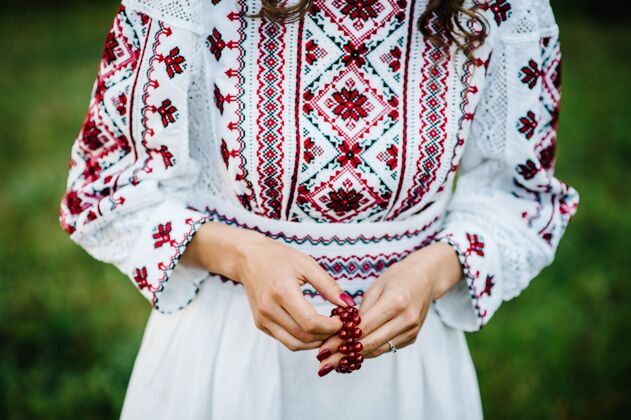 昂贵女性手指甲上涂着红漆 手镯上戴着纯朴风格的宝石优雅公园刺绣
