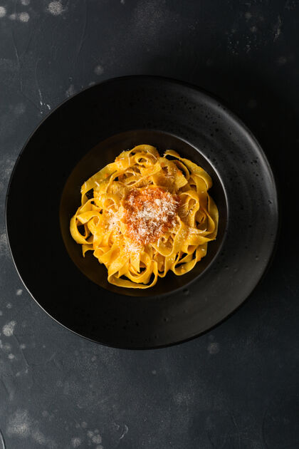 芹菜传统意大利帕萨特沙司和帕尔马干酪的意大利面 黑色盘子 深色表面帕尔玛干酪多样性顶部