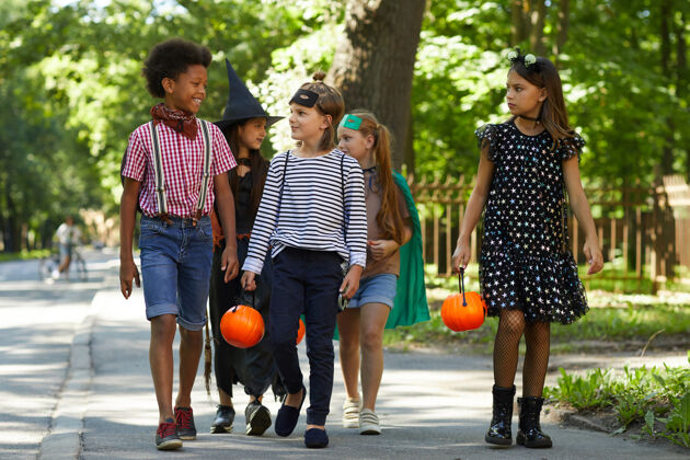 玩耍一群穿着化装的孩子带着玩具南瓜走在街上庆祝万圣节街道孩子城市场景