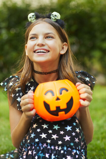 不给糖就捣蛋快乐小女孩的画像 手里拿着玩具南瓜 在户外玩得很开心庆祝幽灵十月
