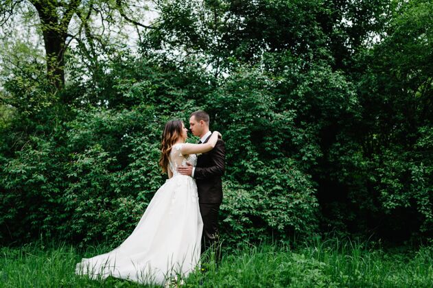 公园年轻的新婚夫妇在大自然的肖像新娘花时尚