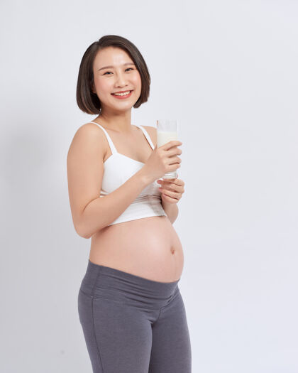 妈妈怀孕的年轻亚洲女人手里拿着一杯牛奶健康女人分娩