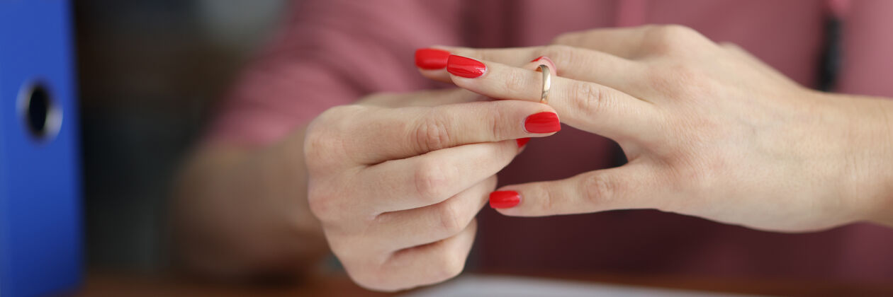 法律在文件特写镜头前从手指上摘下婚戒的女人法官手指律师