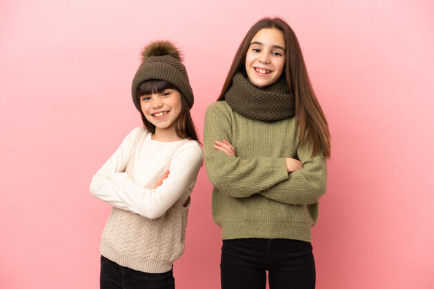 年轻小姐妹们穿着一件粉色背景的冬装 双臂交叉在前面自信小站立