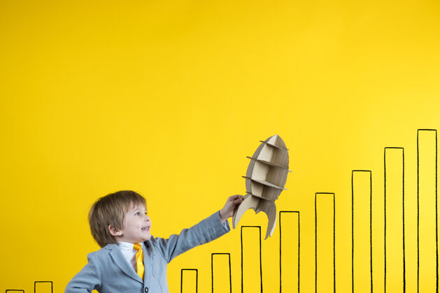 梦想快乐的孩子拿着纸火箭对着黄色的表面动机科技解决方案