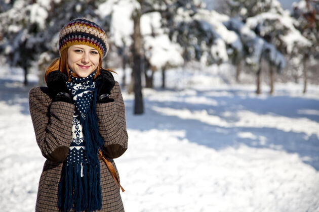 皮肤美丽的年轻红发女子在冬季公园可爱脸围巾
