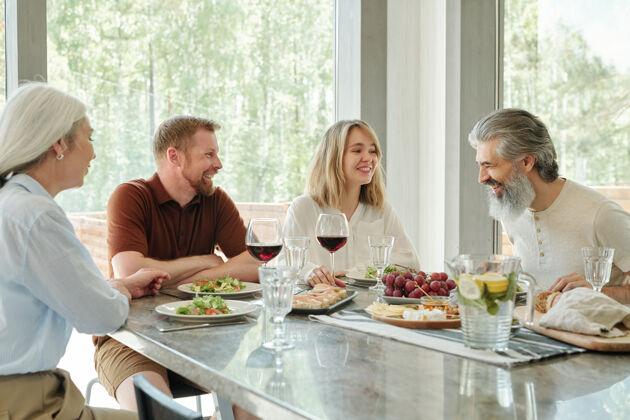 食物快乐的一家人坐在乡间小屋的一张桌子旁 边吃边聊人群人人的年龄