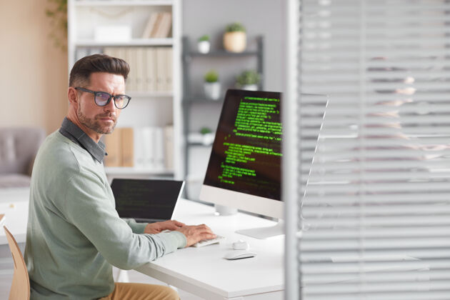 商务人员在软件开发公司里 一个成熟的开发人员坐在桌子前看着电脑的画像软件无线技术商务人员