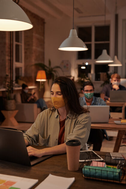 微笑在流感大流行期间 一群戴着防护面具的商人坐在工作场所 在办公室里操作电脑商务计算机专业职业