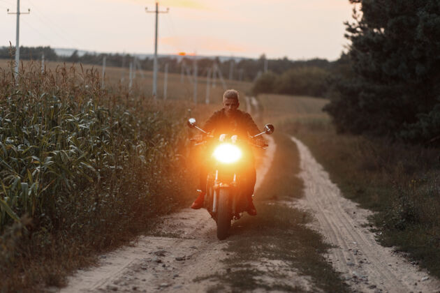 运动一个骑着摩托车的男人在田野里放光摩托车夹克冒险