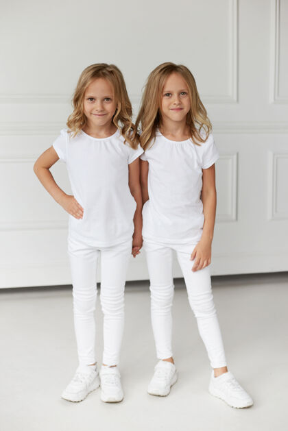 姿势一对穿着白色衣服的双胞胎姐妹手牵手的完整图像可爱家庭小