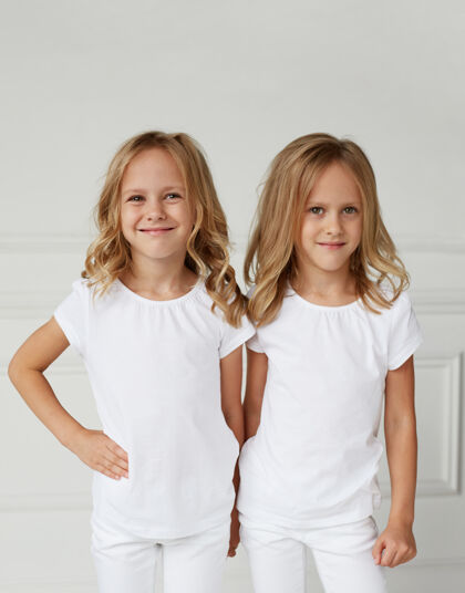 姿势两个穿着白衣服微笑的小女孩时尚金发年轻