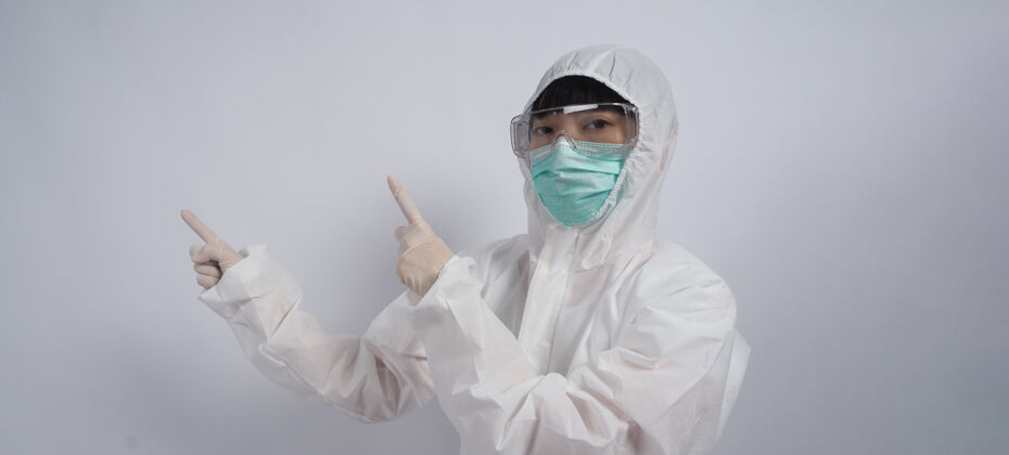 手医生手势穿着ppe套装或个人防护装备的亚洲女医生手势和指点外白医用橡胶手套 护目镜眼镜和绿色n95口罩保护大流行的冠状病毒成功流行面具