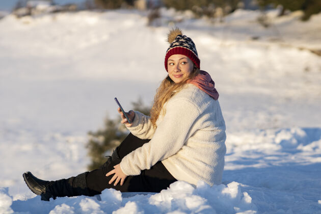 雪雪地里拿着手机的女人移动美丽外套