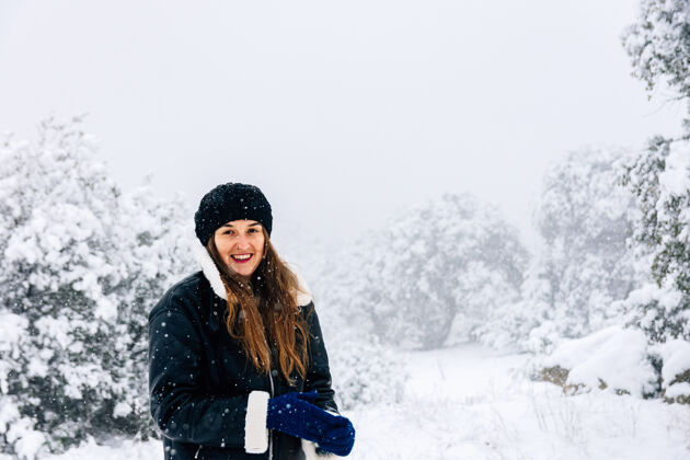 穿上一个美丽的女人在下雪时用手机拍照的画像凉爽金发孤独