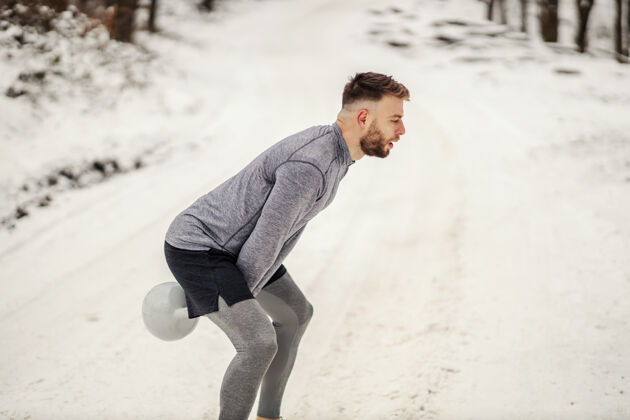 活力一名运动员站在雪地小道上摇动壶铃冬季健身 冬季运动 健身寒冷秋千运动员