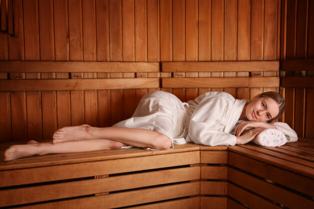 传统躺在桑拿房木凳上的年轻女子热放松按摩