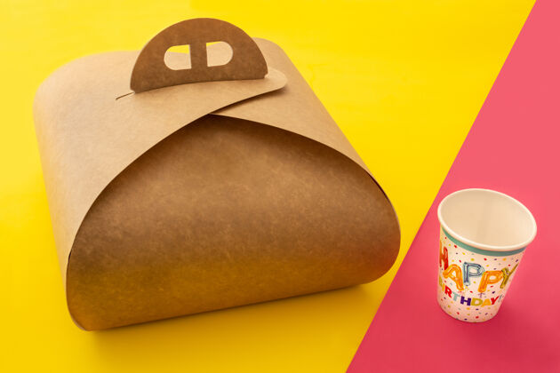美味黄色和粉色桌子上的蛋糕和纸杯的带把手的包装盒模型包装纸板馅饼