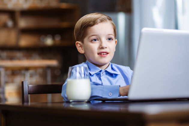 碗快乐的小男孩在厨房休息时用笔记本电脑养育室内烹饪
