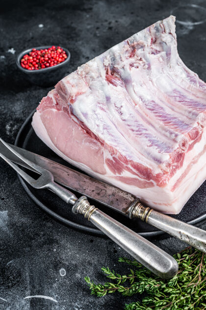 肉新鲜生的整排猪里脊排骨放在一个带肉叉的盘子里牛排生的食物