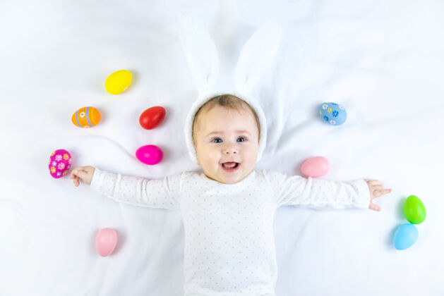 幼儿宝宝穿得像兔子 在白色的表面上放复活节彩蛋小有趣多彩