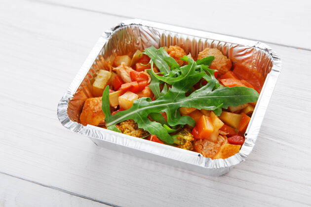 餐具把食物放在锡箔盒里 蔬菜炖在白木上 用酱油 番茄酱和芝麻菜烹饪美食西红柿