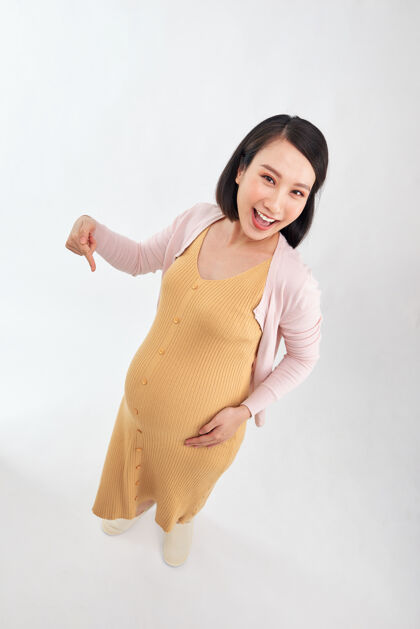胃快乐的年轻孕妇在白色的背景下 女人手指着肚子美丽快乐父母
