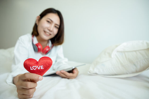 年轻亚洲美女在情人节用平板电脑买礼物 在卧室里展示爱心文字肖像女人爱