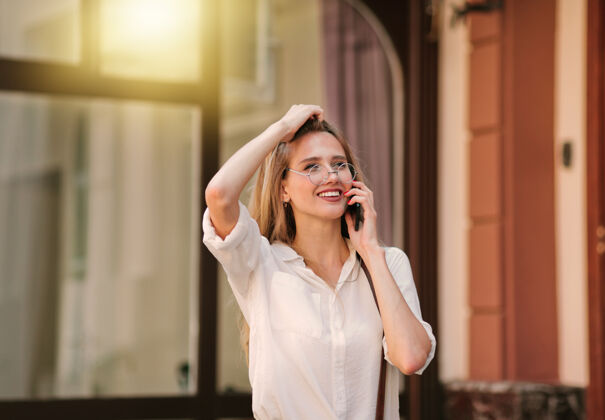 手机开朗微笑的金发女人在户外打电话女人户外成年人
