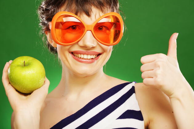快乐带着绿苹果在绿地上微笑的年轻女子水果欧洲苹果