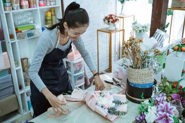 信心在花店工作的微笑女花匠在桌子工作区定做法兰绒花围裙成人女性