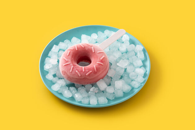 棒棒糖黄色桌子上的草莓甜甜圈冰棒和碎冰圆形奶油冷