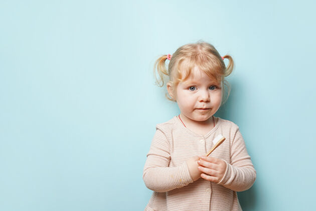 儿童可爱的女婴拿着牙刷在蓝色的表面刷牙日常牙刷表达