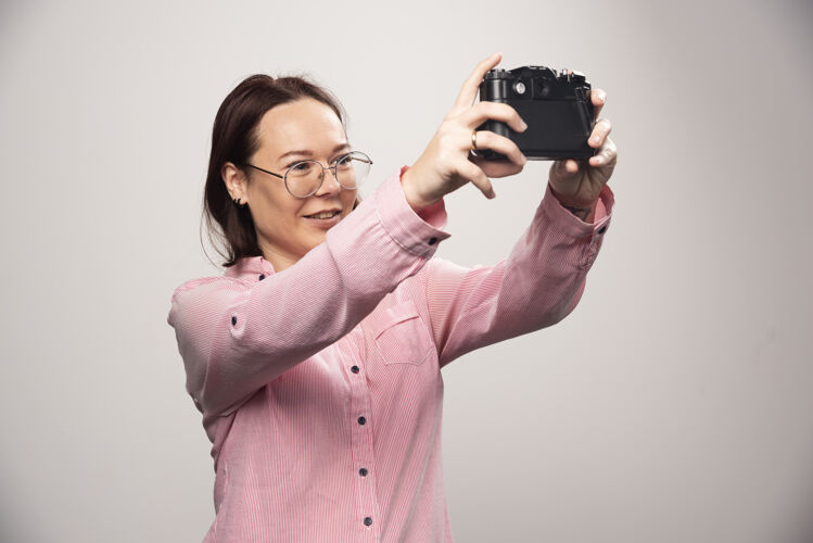 女人一个女人用相机在一张白色的高质量照片上自拍可爱时尚肖像