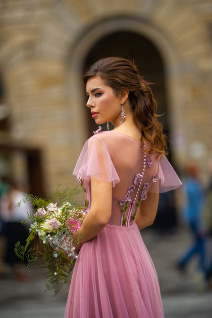魅力意大利佛罗伦萨古城中心站着一位身穿粉色礼服 手持花束的新娘浪漫肖像花束