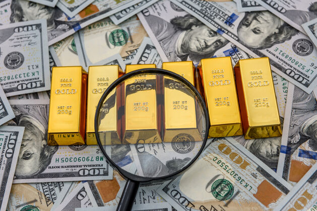 投资带放大镜的美元钞票上的金条 黄金或铸锭货币放大镜现金