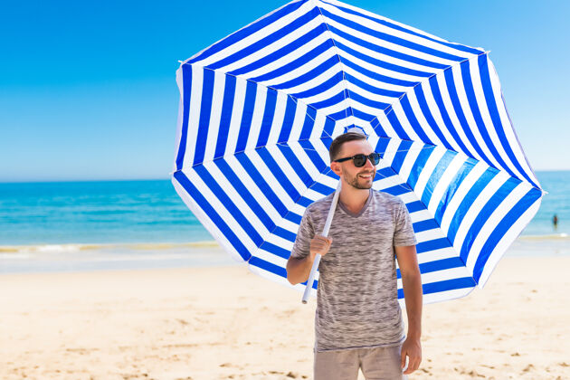 热带戴墨镜的年轻人打着太阳伞在沙滩上散步胡须海滩快乐
